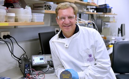 A scientist wearing a lab coat and holding a piece of equipment